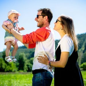 man in white and red polo shirt carrying girl in blue denim jeans during daytime